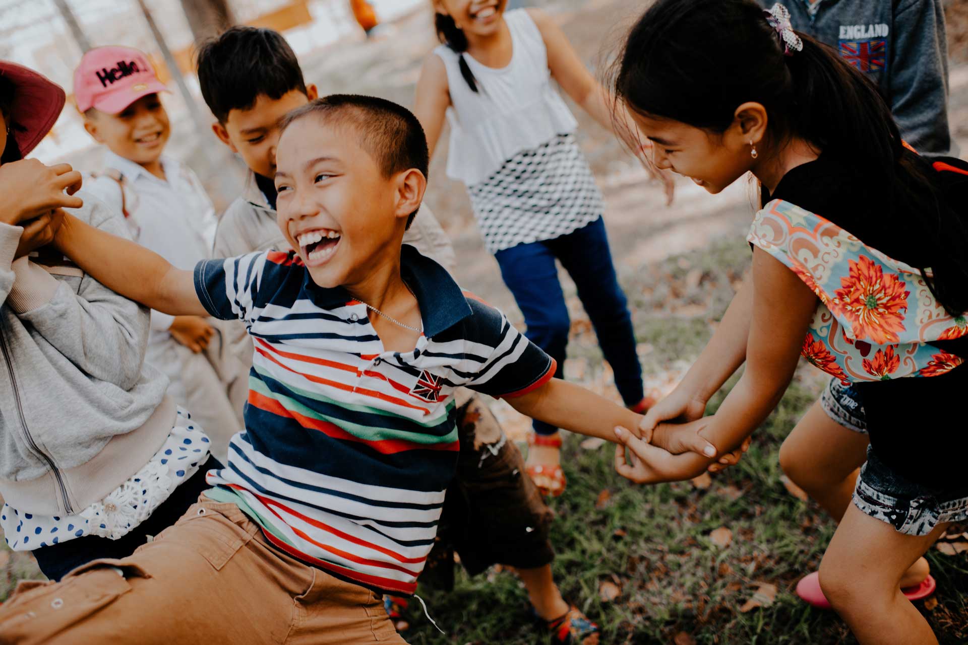 young boy smiling while having his arm pulled by two girls