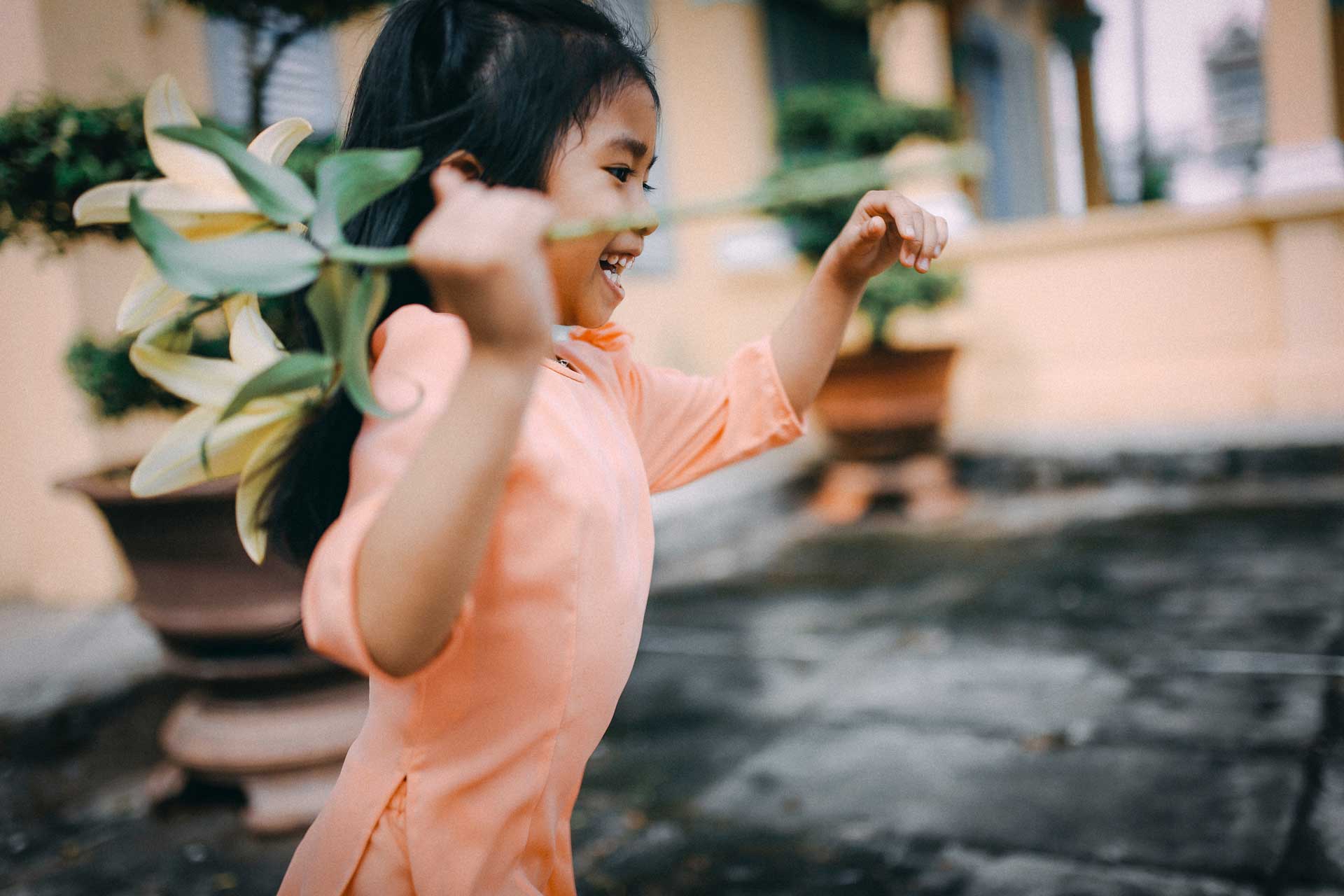 young girl in peach dress running with flower