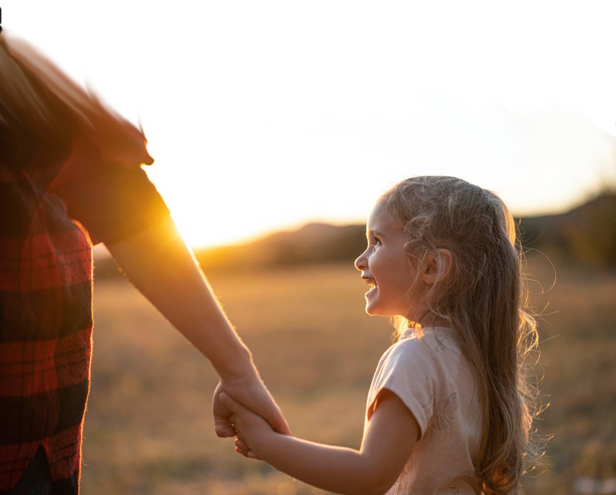 happy child holding mom's hand on family hike at sunset